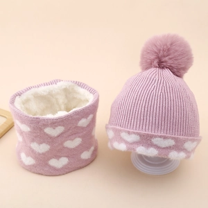 Detail of pink knitted hat and scarf set with heart pattern and warm fleece lining