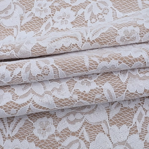 Detailed macro view of white floral lace embroidery with intricate mesh fabric texture