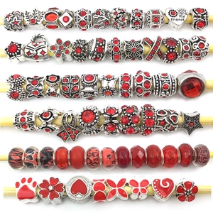 Detailed flat lay of red alloy spacer beads and flower pendants for DIY jewelry