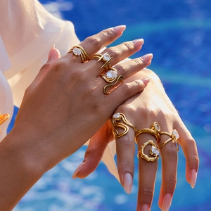 Close-up of gold curved zircon rings on fingers with a blue pool water background