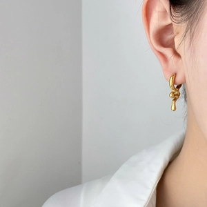 Golden irregular lava style hoop earrings with a glossy finish shown on a model