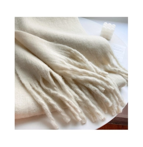 Close-up of beige plush scarf fringe detail with soft textured material and tassels