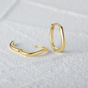Macro shot of gold irregular wave earrings with polished finish and streamline design