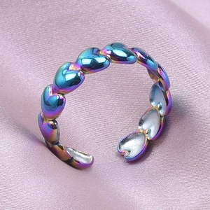 Macro shot of rainbow-plated heart-shaped open ring on soft pink silk background
