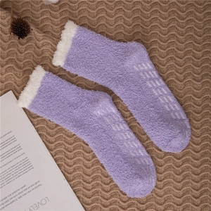 Detailed view of purple coral fleece slipper socks with non-slip grippers on bottom