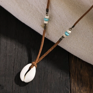 Bohemian velvet cord necklace with white shell pendant and beads on a rustic wooden background
