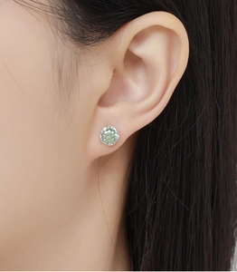 Detail view of light green round cut zircon stud earring on ear with silver setting