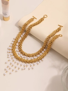 Détail du collier doré multicouche avec glands de perles blanches et fermoir en T