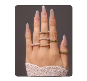 Close-up of stacked stainless steel rings with green and clear zircon stones on model hand
