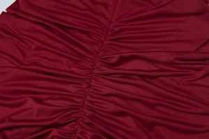 Close-up of dark red gathered fabric showing the smooth pleated texture and fine stitching