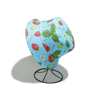 Detail of light blue bucket hat with strawberry print on a metal stand for sun protection