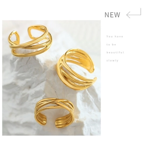 Detail of layered gold-finished cross ring on textured marble background