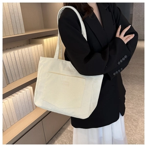 Detail of cream corduroy tote bag featuring a front pocket with XINRUIGOOD logo label