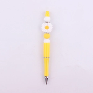 Detail of yellow beaded pen featuring a white daisy flower topper and sparkling rhinestones