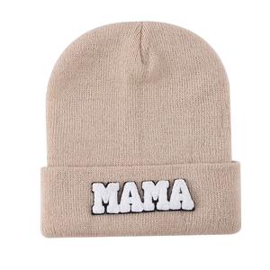 Close-up of MAMA towel embroidered patch on khaki knitted beanie cuff texture