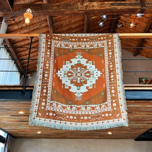Close-up of bohemian woven blanket with orange geometric patterns and tassel details