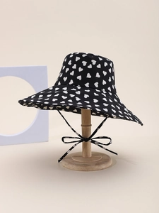 Detail of black wide brim sun hat with white heart pattern and adjustable chin strap