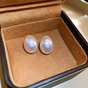 Gros plan de boucles d'oreilles perles gouttes aux reflets irisés dans un écrin en velours