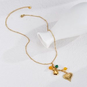 Bohemian gold layered heart pendant necklace with colorful beads on a white vase
