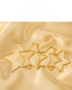 Détail macro de boucles d'oreilles étoile plaquées or 18K sur fond de satin lisse