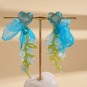 Blue chiffon heart beaded tassel earrings with fabric bow on a gold display stand