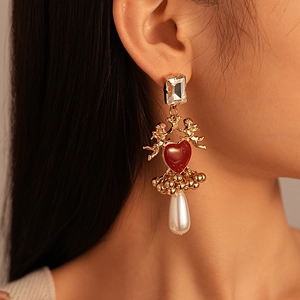 Vue détaillée de boucles d'oreilles ange vintage avec cœur rouge et perle en goutte