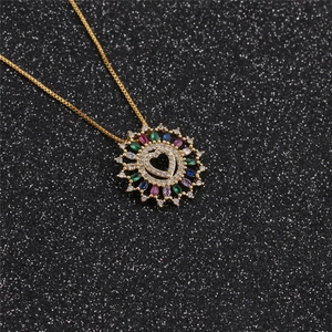 Macro shot of gold sunburst heart pendant with colorful cubic zirconia on black glitter