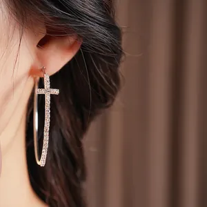 Orecchini a cerchio in argento con croce incastonata di cristalli su una modella