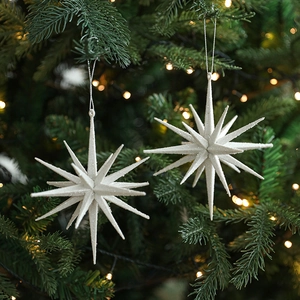 Stereoscopic glittery star pendants hanging on a Christmas tree with warm lights