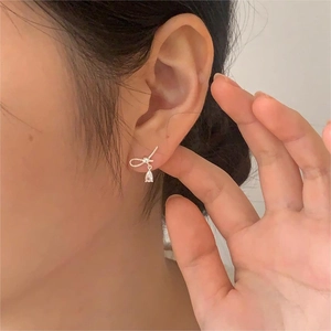 Detail of silver bow earrings with pear-cut drop stones worn by a female model