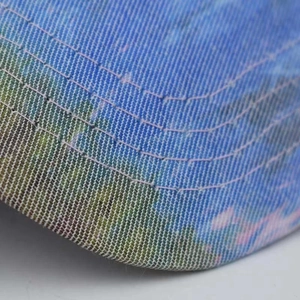 Detail of cross ponytail cap showing oil painting landscape print and reinforced stitching