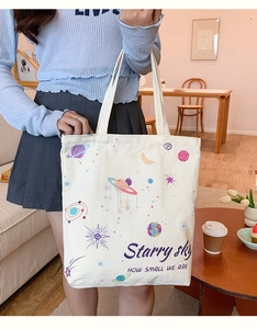 Detail of white canvas tote bag with colorful planet print and starry sky slogan