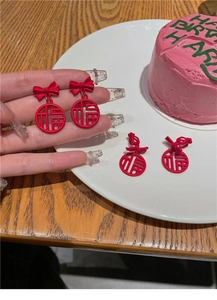 Detailed view of red bow earrings with hollow round frame and Chinese Fu character