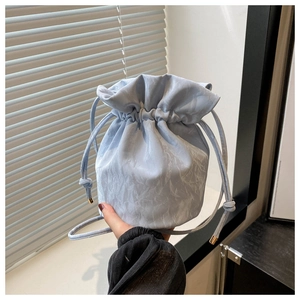 Detail of light blue drawstring bucket bag with pleated texture and golden hardware