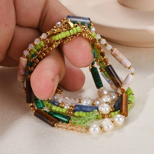 Detail of layered natural pearl bracelets with colorful beads and gold chain on hand