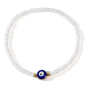 Ethnic white seed bead bracelet with blue evil eye charm and golden accents on white background