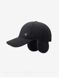 Detail view of winter baseball cap with earflaps and silver metal logo on woven fabric