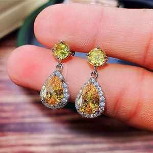 Close-up of yellow teardrop-shaped zircon earrings with pavé diamond halo setting