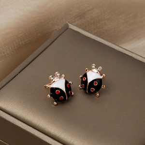 Gros plan de boucles d'oreilles coccinelle avec émail et cristaux sur boîte
