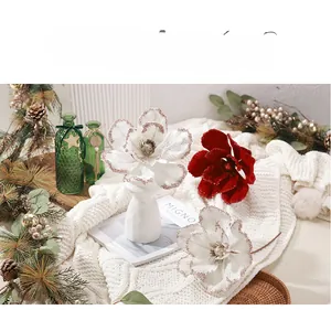 Close-up of red and white velvet Christmas flowers with gold glitter in a ceramic vase