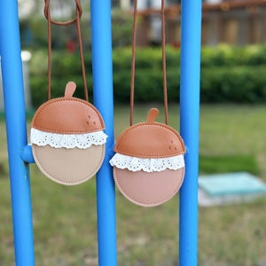 Detail of acorn-shaped mini bags in brown, pink, and beige with lace trim and woven straps