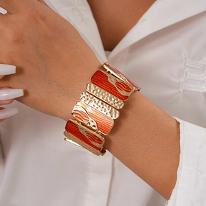 Detail of bohemian gold hammered metal and orange enamel geometric stretch bracelet