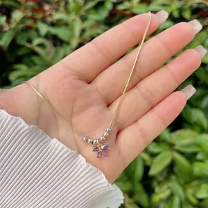 Detail of 18K gold plated necklace featuring purple bow crystal and mixed metal beads