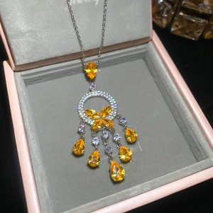 Detailed view of butterfly droplet necklace with yellow gems in pink jewelry box