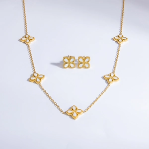 Detail of 18k gold clover necklace and earrings set with white shell inlay