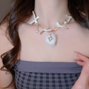 Detail of white ribbon bows, pearls, and plush ball pendant with heart crystal necklace