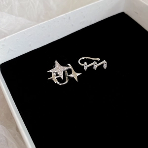 Detail of silver asymmetric star ear cuffs with zircon and pearls in jewelry box