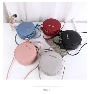 Flat lay of colorful round crossbody bags with bow handles and litchi texture