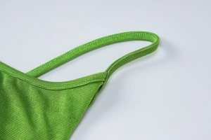 Gros plan sur la texture en tricot vert vif et la fine bretelle de la robe