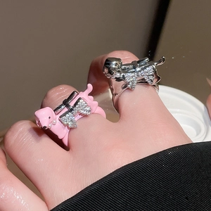 Close-up of cute dachshund dog rings with zircon bows in pink enamel and silver finish